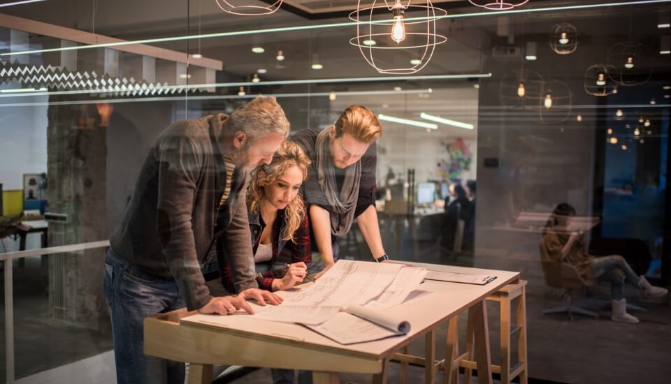 three people looking at a paper printout discussing what website architecture is