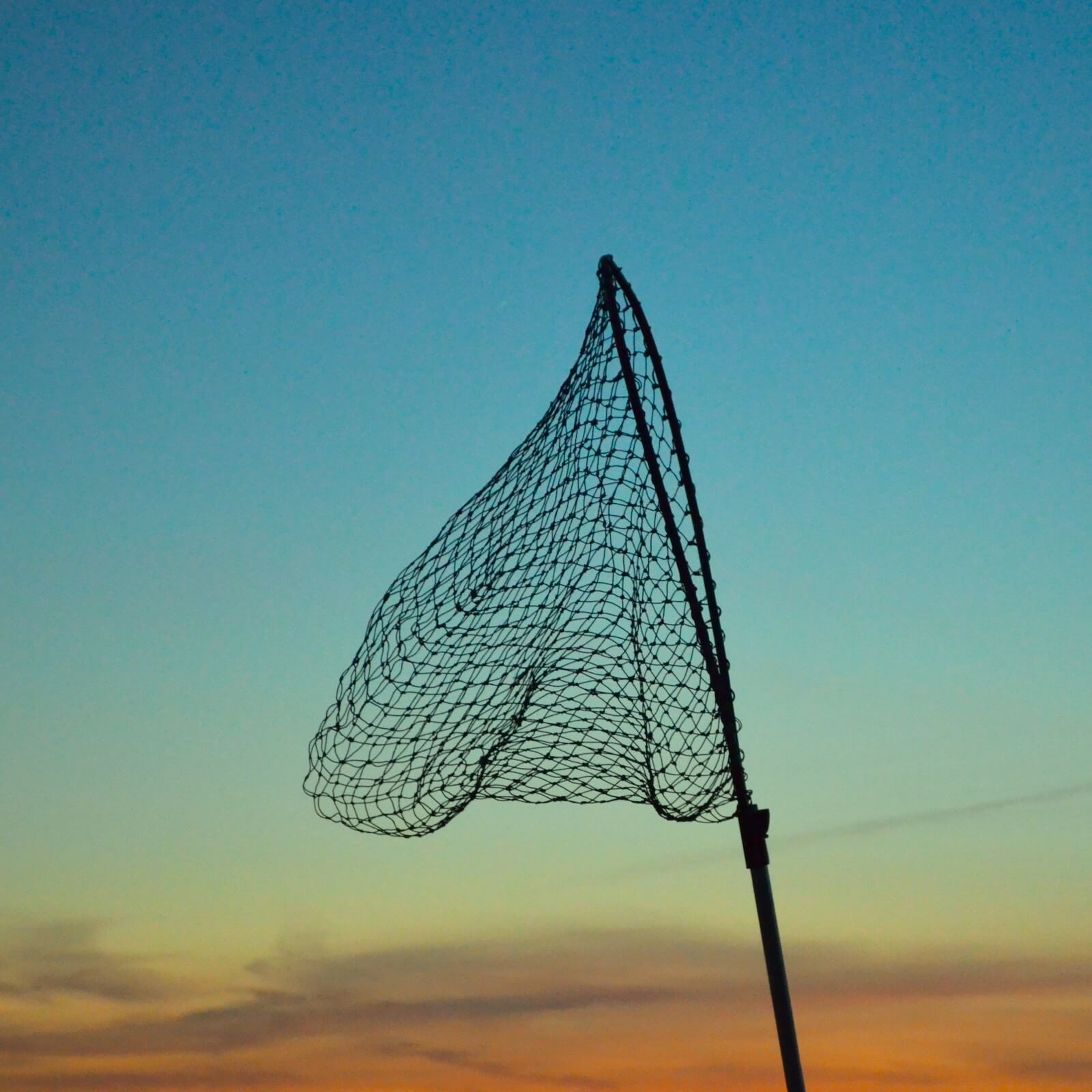 A fishing net in front of a blue sky at sunset