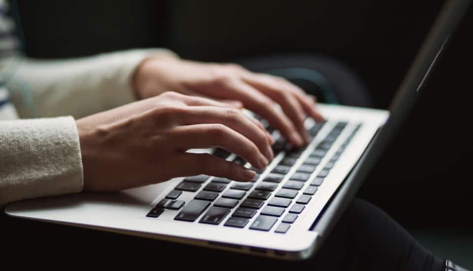 woman writing an article on a laptop about the benefits of content marketing