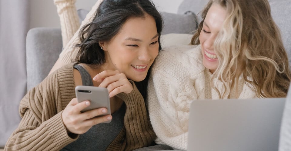 two women smiling while looking at entertaining ecommerce content marketing