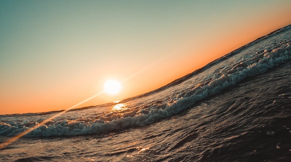 wave with setting sun on horizon