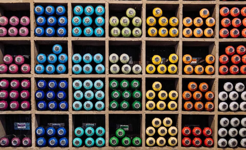 bottles organized by color in wood compartments.