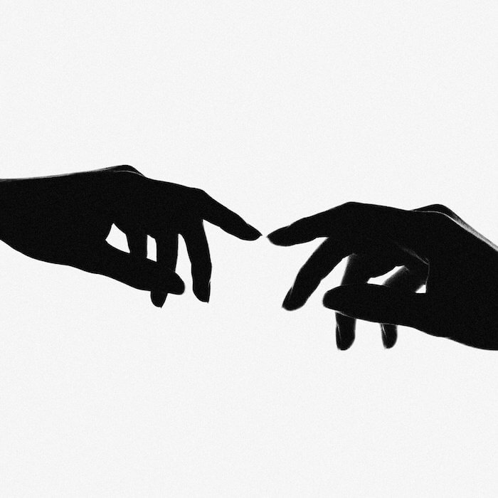silhouette of two hands touching against a white background