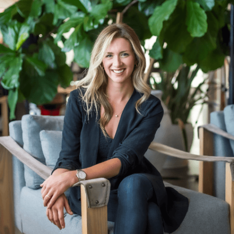 Blonde woman sits and smiles at the camera