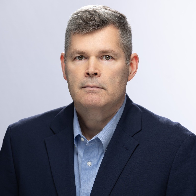 A man in a suit looks into the camera