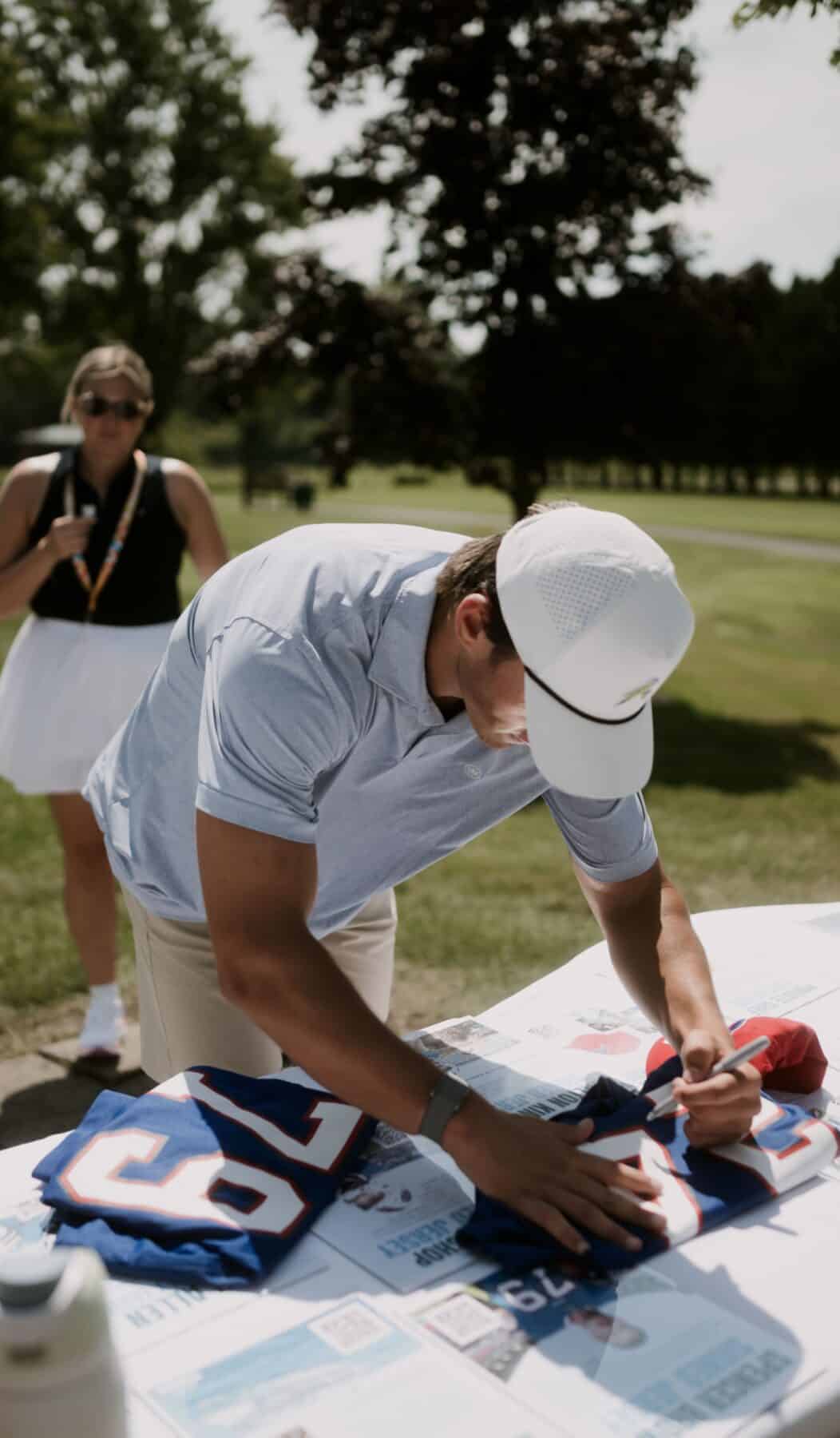 A man signs a footbal jersey